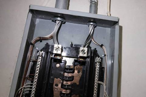 Main lugs at the top of a panel with two large service conductors landed in them, deadfront removed